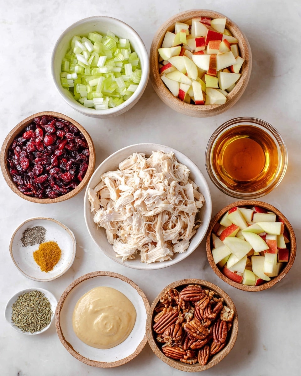 A top view of several small bowls with ingredients arranged on a white marbled surface. The largest bowl in the center holds shredded pale beige chicken. Surrounding it are a white bowl with chopped light green celery, a wooden bowl with red dried cranberries, another wooden bowl with chopped red and yellow apple pieces, and one more wooden bowl with chopped brown pecans. Small white bowls contain a smooth beige creamy mixture and light yellow mustard. A shallow white plate with black pepper and salt is placed next to a glass bowl of amber liquid. Another wooden bowl holds three spices: pale yellow, rusty red, and dark green dried herbs. Photo taken with an iphone --ar 4:5 --v 7