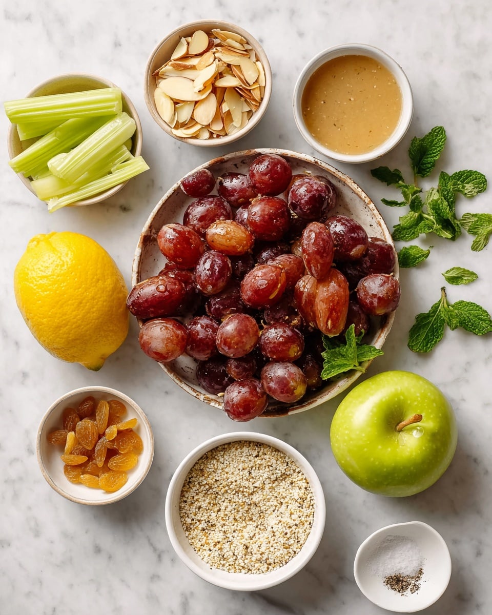 A top-down view shows an arrangement of fresh and dry ingredients on a white marbled surface. There is a cluster of deep red grapes in the center-bottom surrounded by a halved and whole bright yellow lemon on the left. To the right of the grapes is a shiny green apple with fresh green mint leaves around it. Above the grapes and lemon is a medium red apple. Small white bowls hold various items: sliced green celery in the top-left, thin almond slices in the top-right, small golden raisins in the bottom-right, a bowl with a light brown liquid next to the green apple, a bowl of white quinoa grains below the celery, and a bowl of light beige tahini sauce at the bottom. A small white dish with pepper and salt sits near the tahini bowl. The entire setup is clean and bright. Photo taken with an iphone --ar 4:5 --v 7